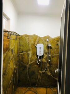 Walk-in shower in the stone-finished bathroom at Villa Komba Upstairs