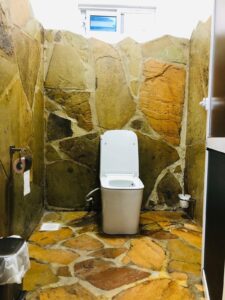 Stone-finished bathroom with toilet at Villa Komba Upstairs