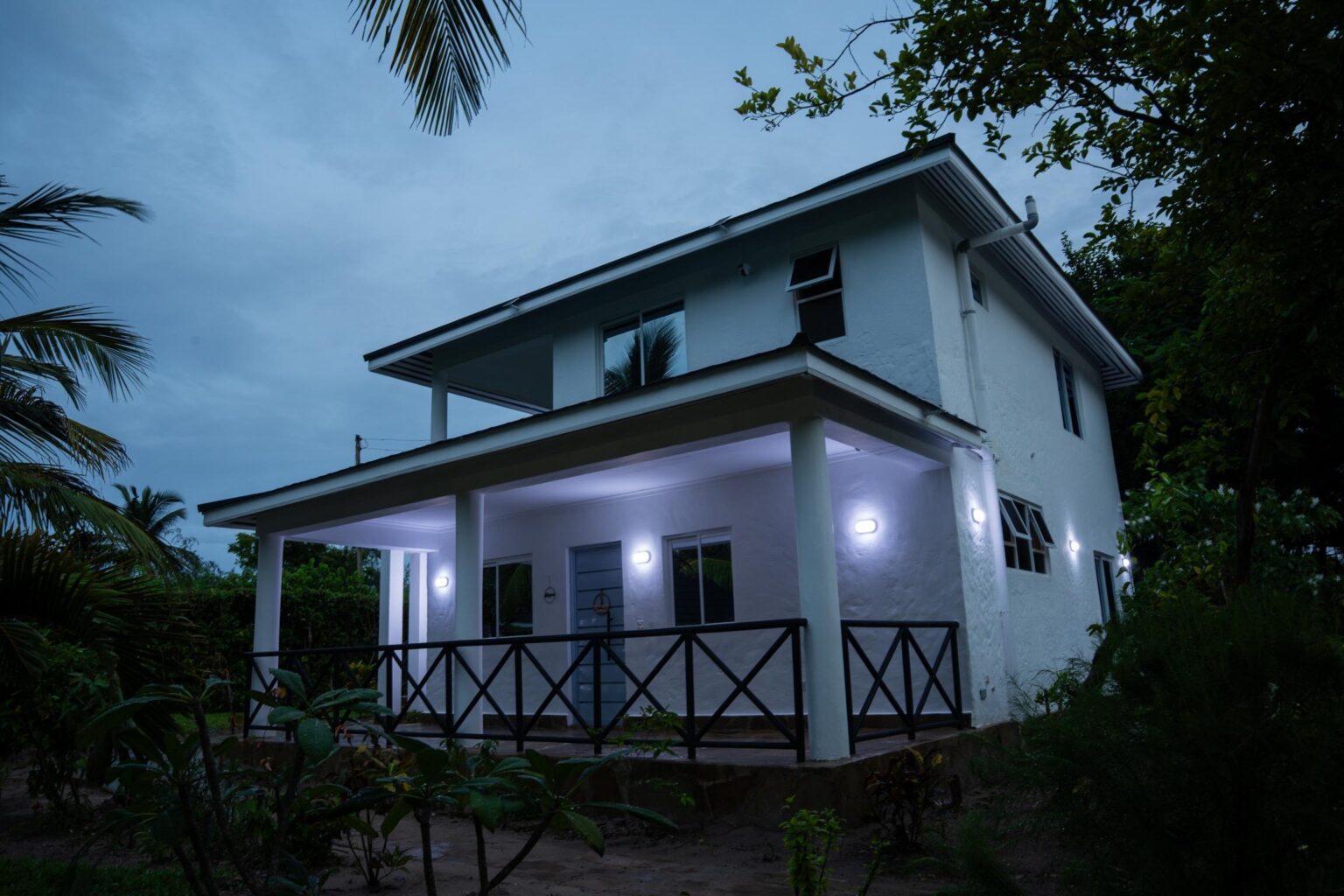 Illuminated accommodation building among palm trees at dusk